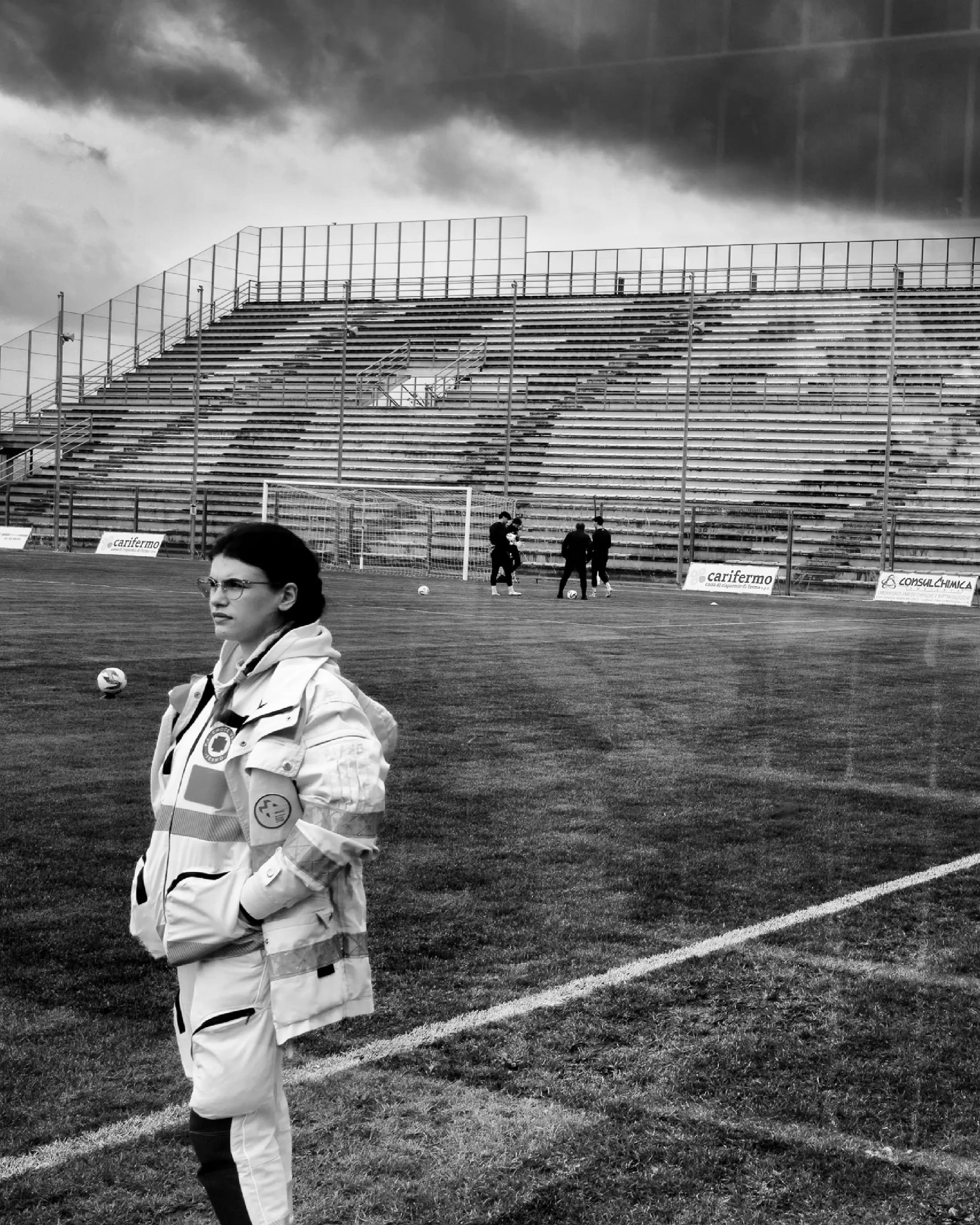 Volunteer on duty at the edge of an empty stadium pitch