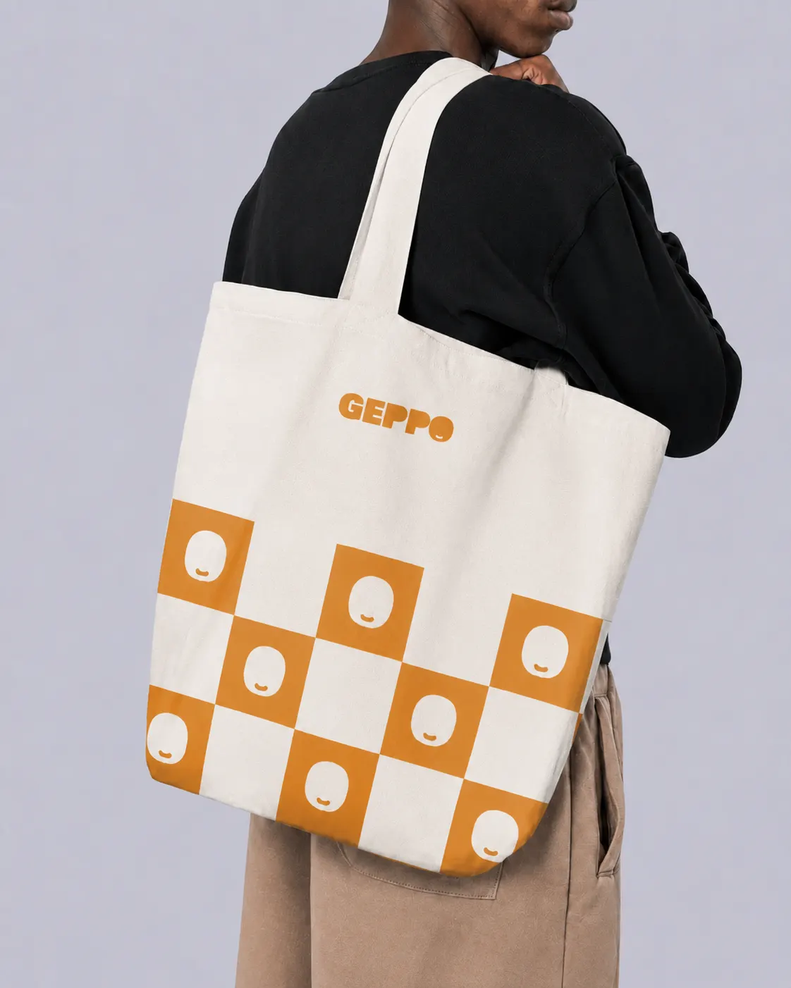 Tote bag with an orange checked pattern and the Geppo mark, worn
