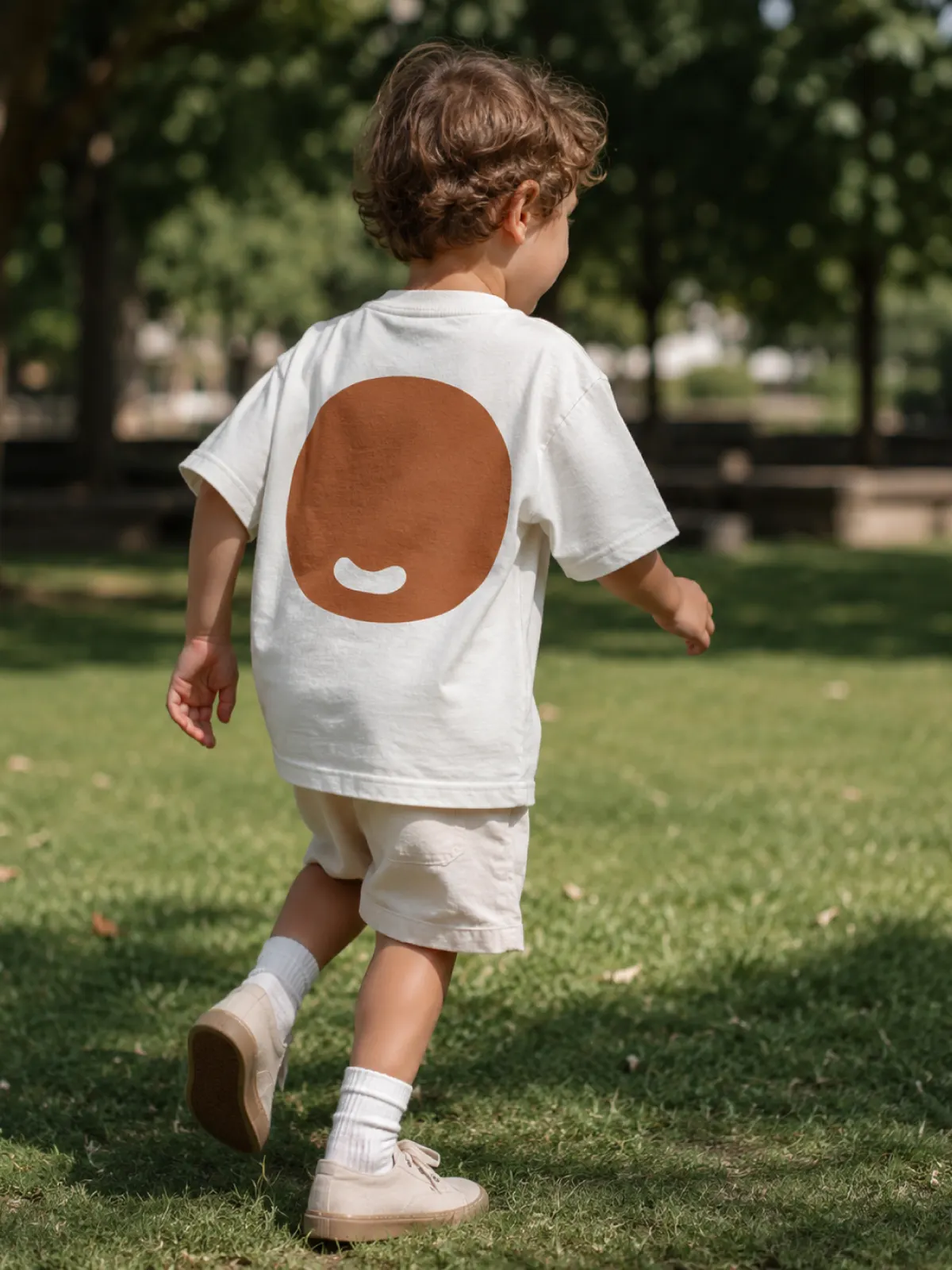 Child running away across a lawn, t-shirt with the brand’s O