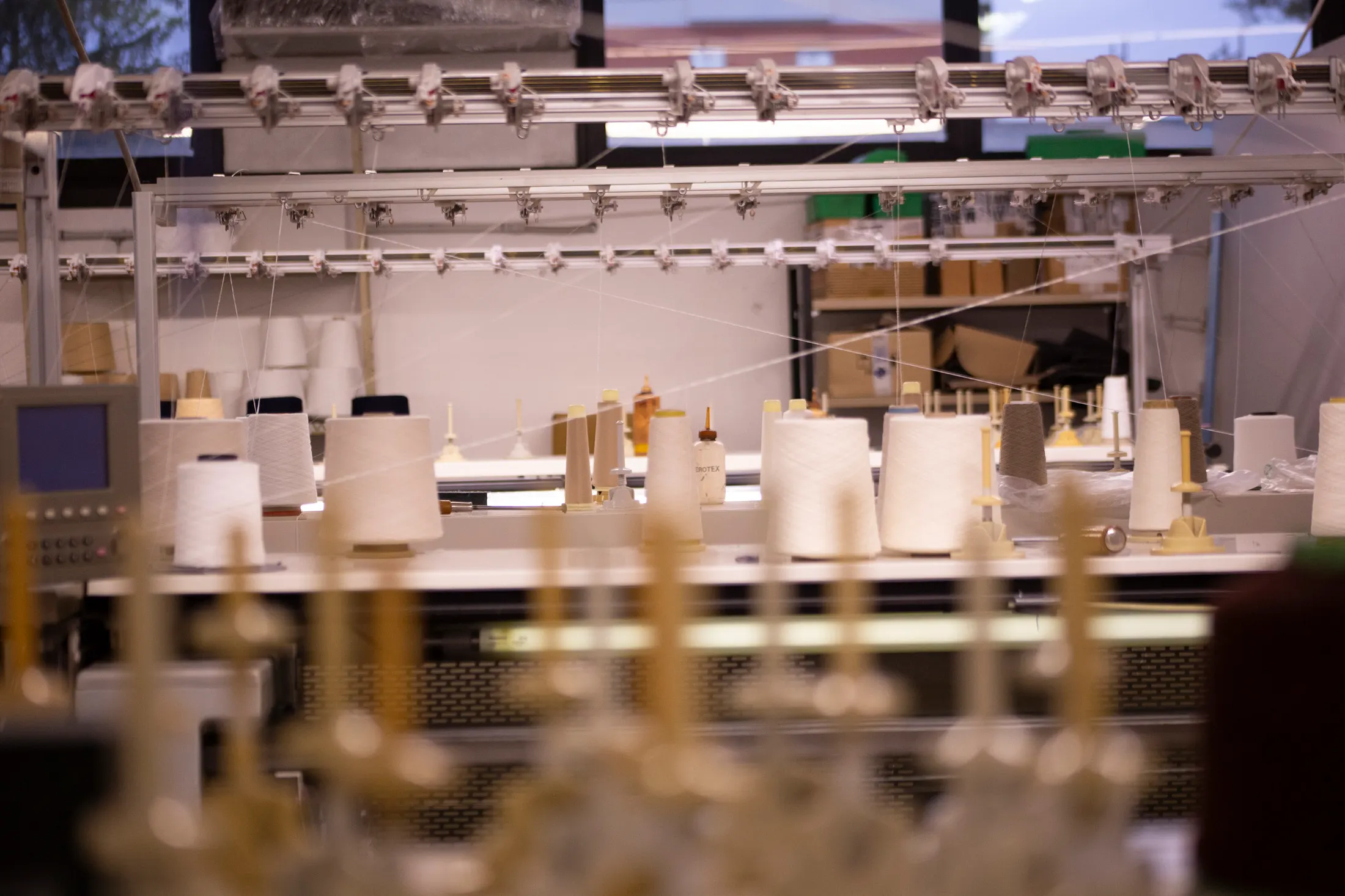 Technician at the circular knitting machine among yarn cones, black and white