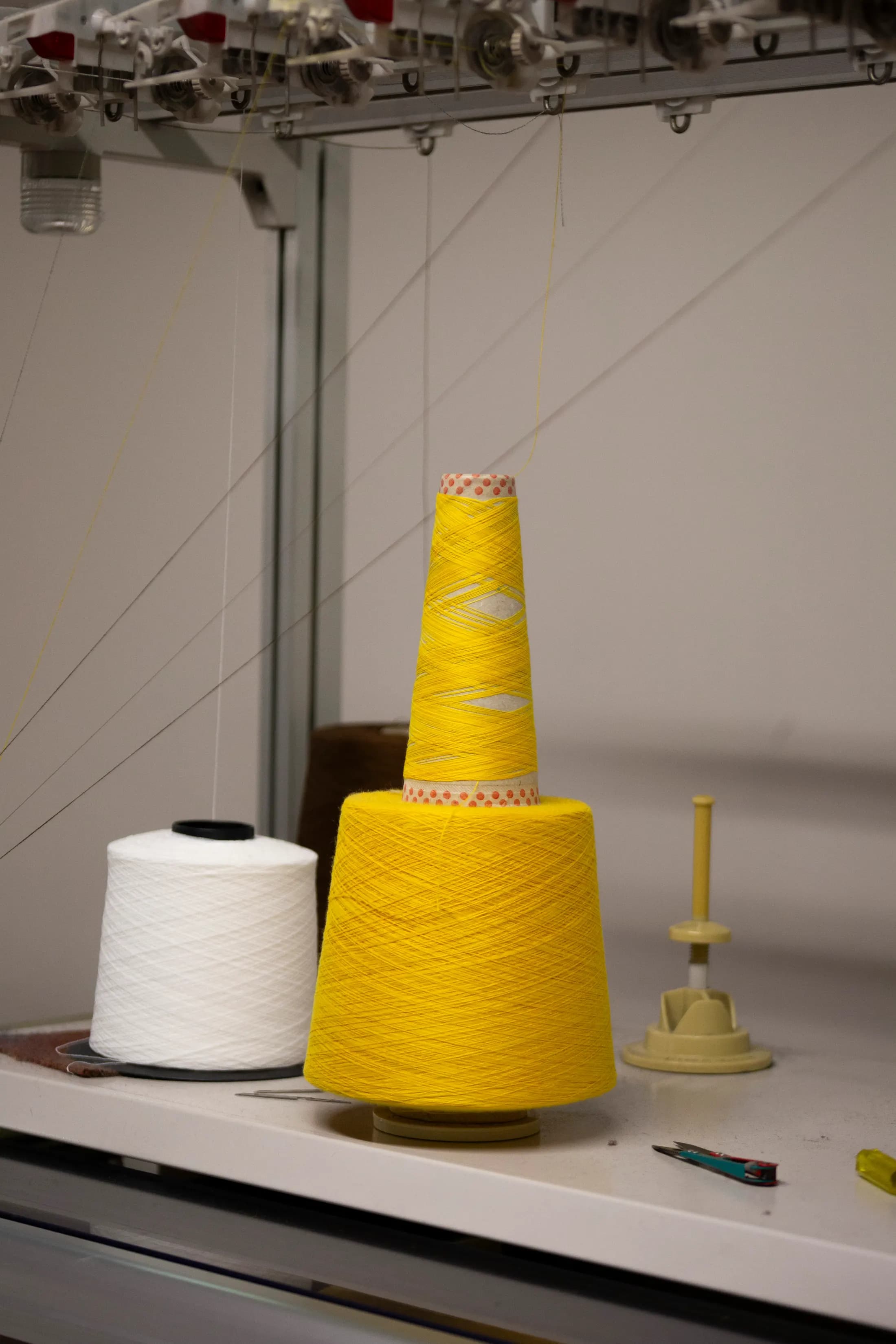 Yellow yarn cone beside a white one on a workbench