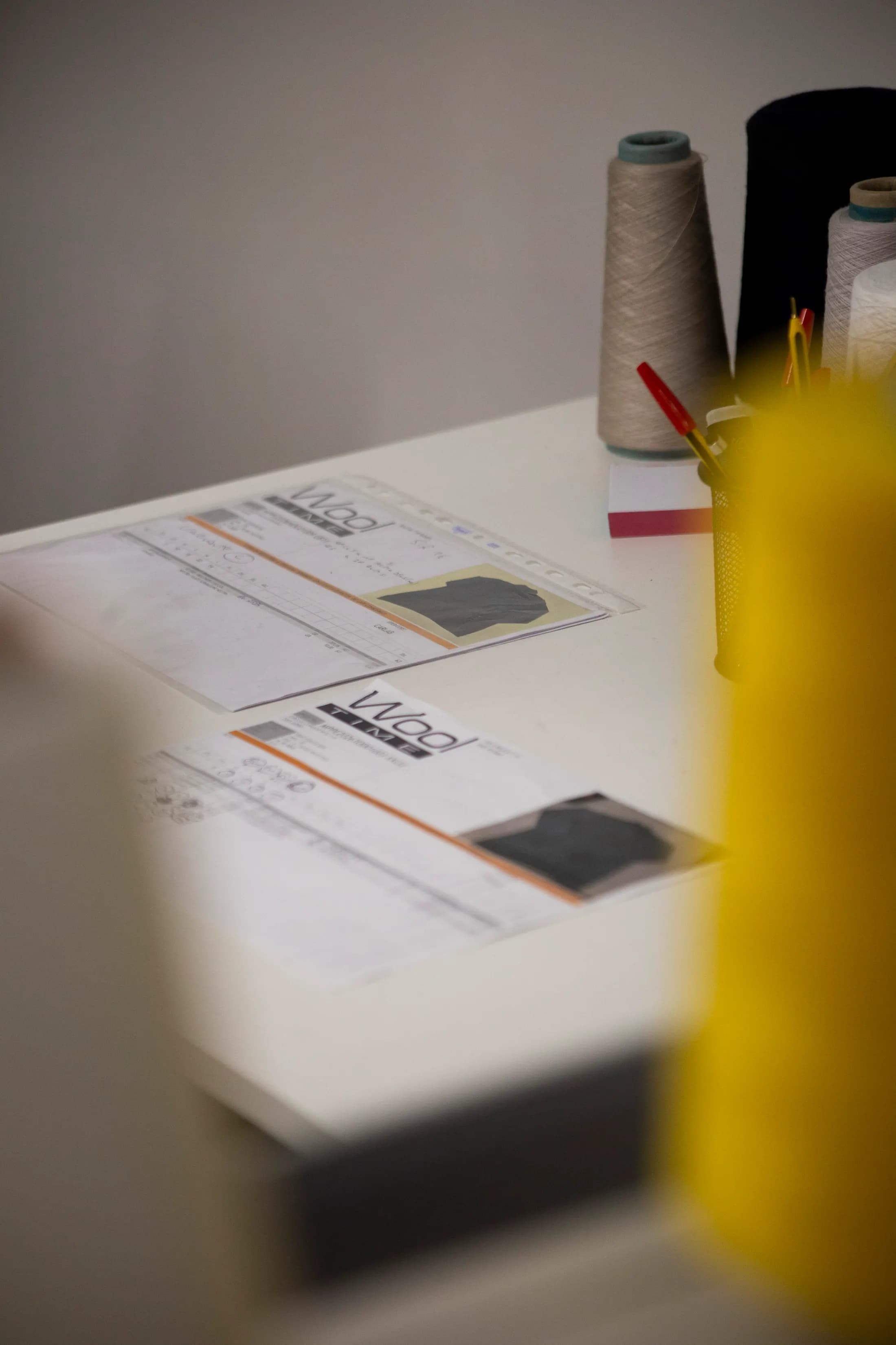 Spec sheet with yarn samples on a table, blurred cones in the foreground