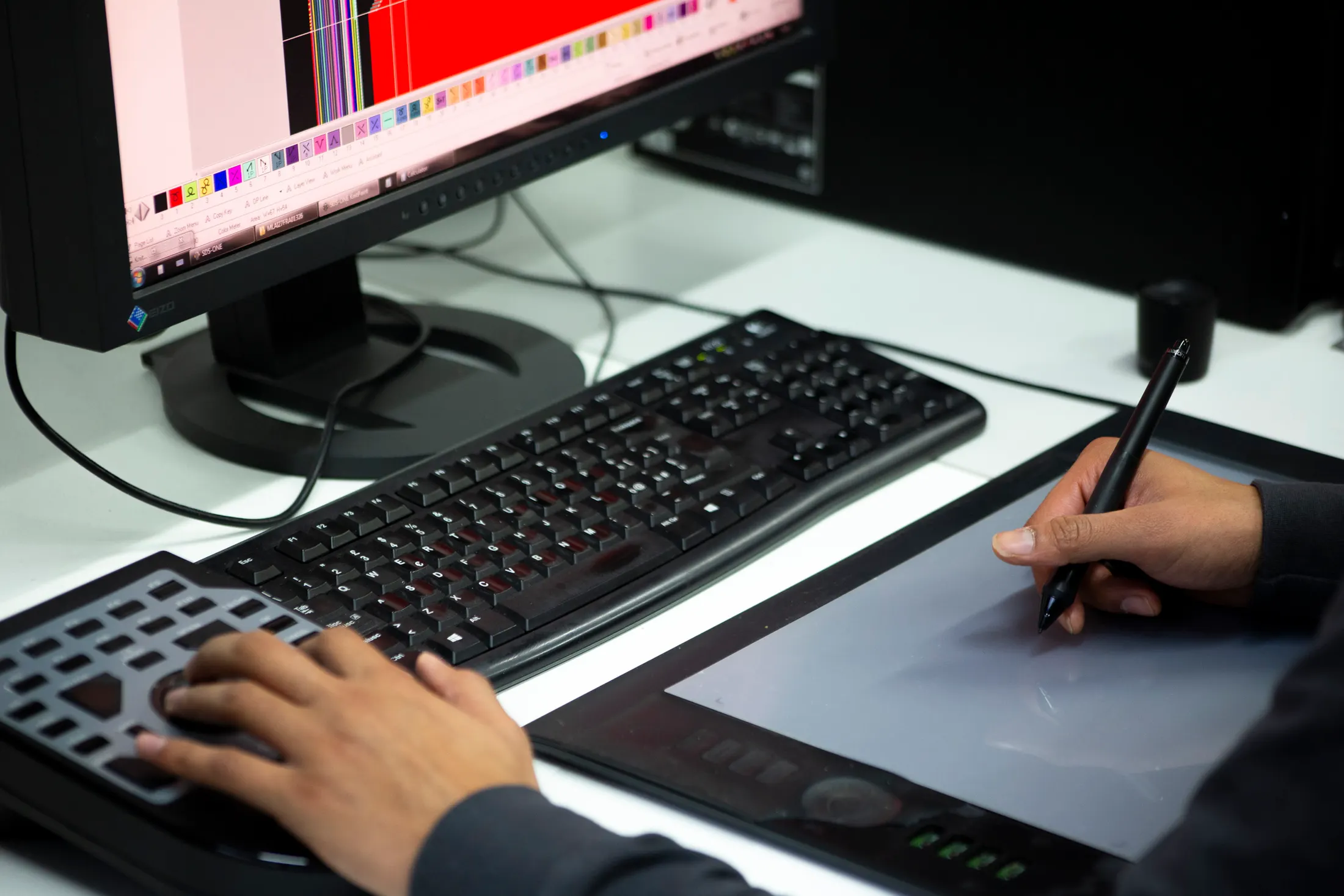Hand drawing on a graphics tablet in front of a screen showing the colour range