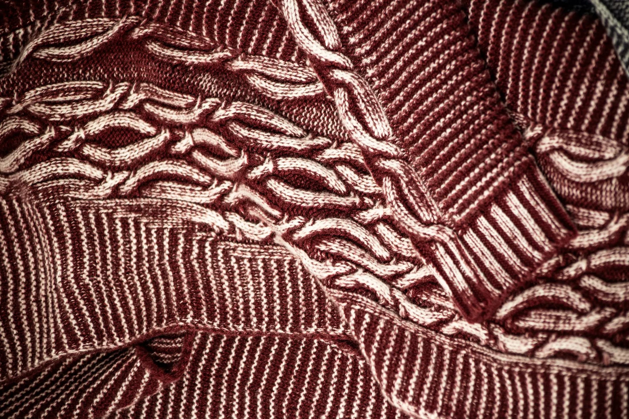 Close detail of burgundy knitwear with a worked stitch
