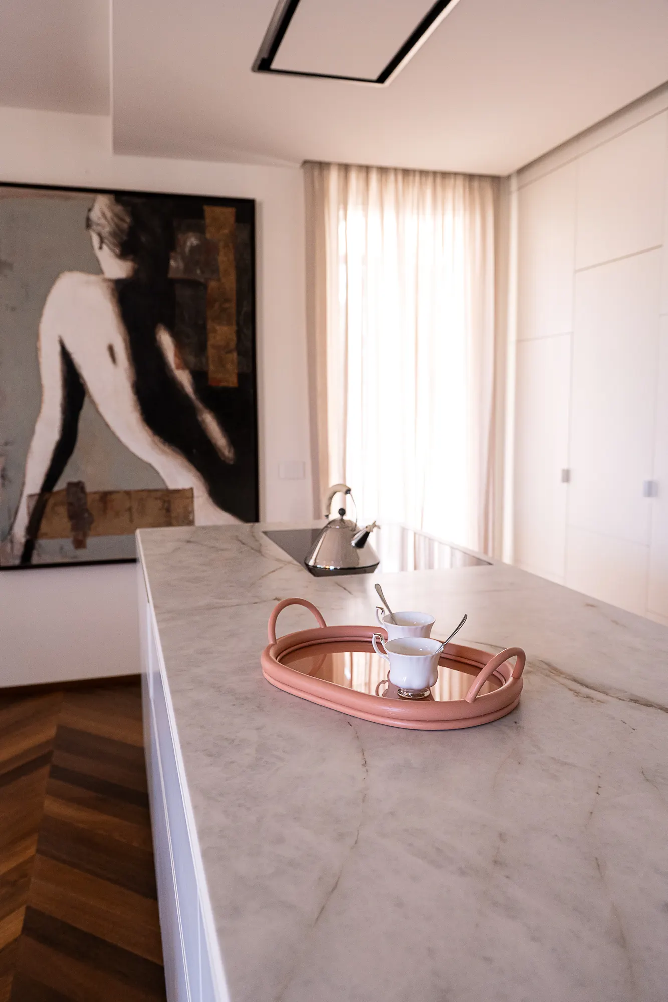 Pink tray on a white marble counter, artwork on the wall behind