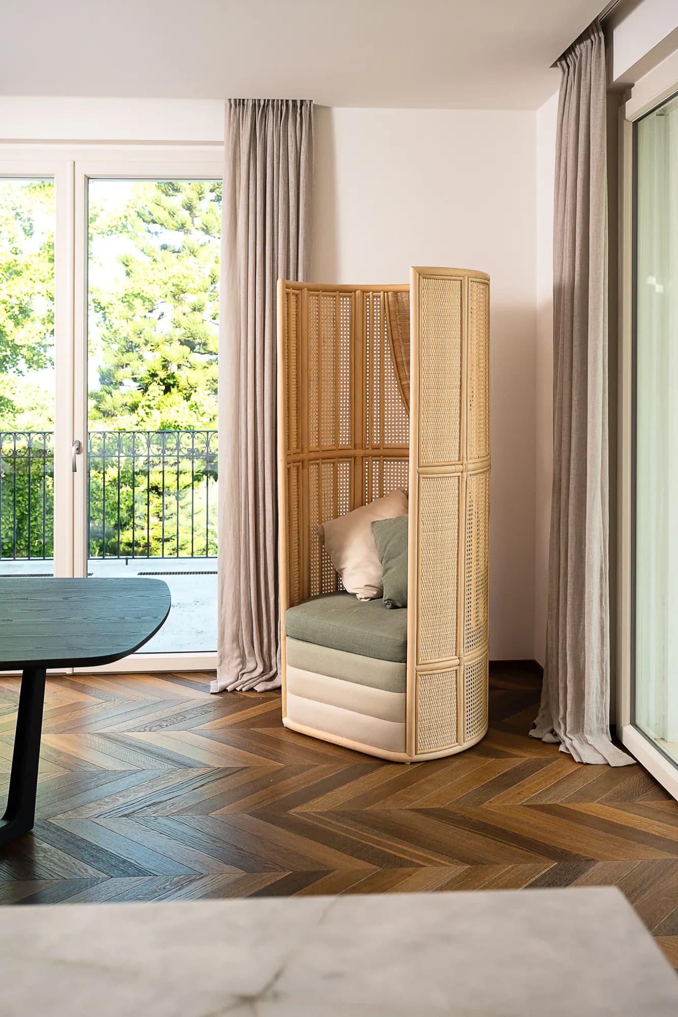 Woven screen armchair in a room with herringbone parquet and a window onto the garden
