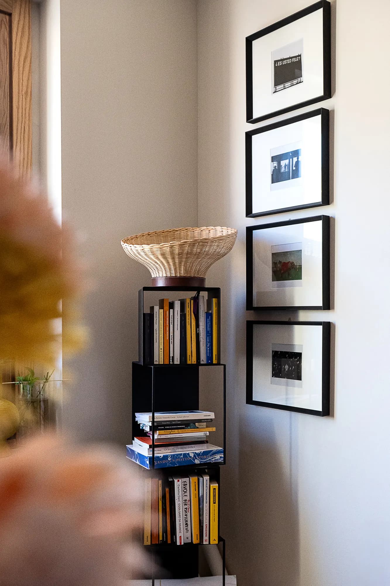 Woven basket lamp on a bookshelf, beside framed prints