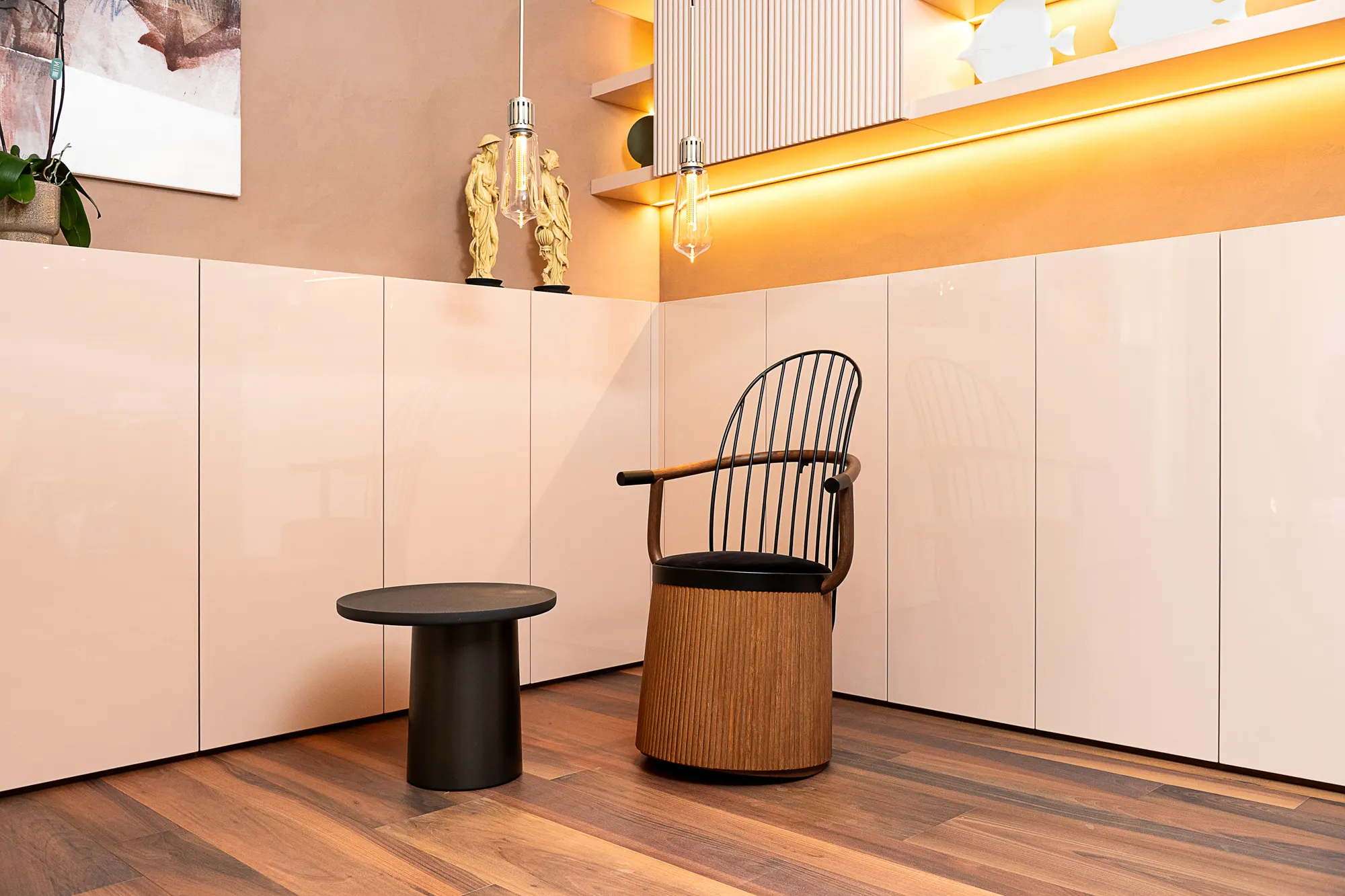 Chair with a woven seat in a pink lacquered kitchen, black side table and wooden floor