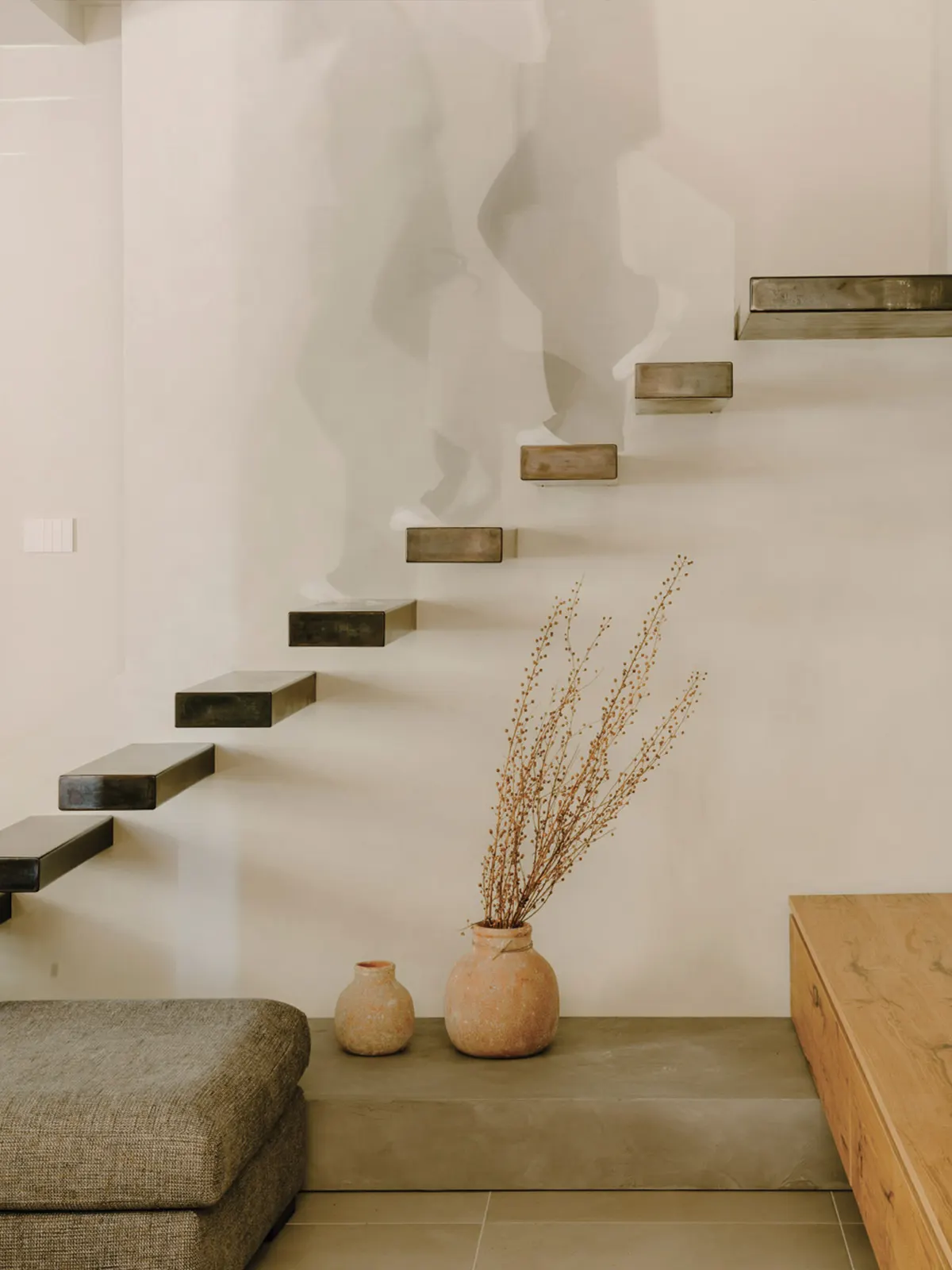Wooden staircase on a curved wall with vases and dried flowers