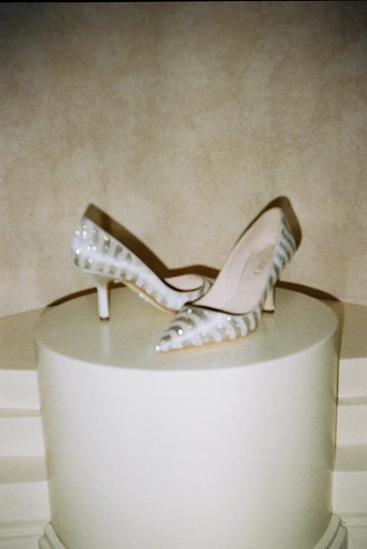 Shot on film: crystal sandals on a white column, soft light