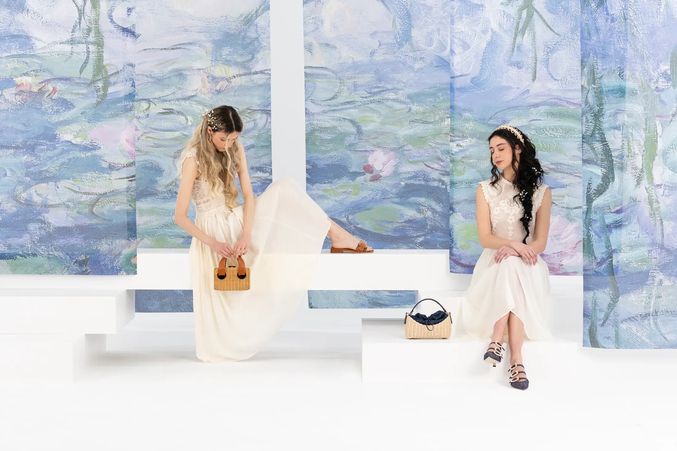 Two models seated on white plinths in front of the water lilies triptych