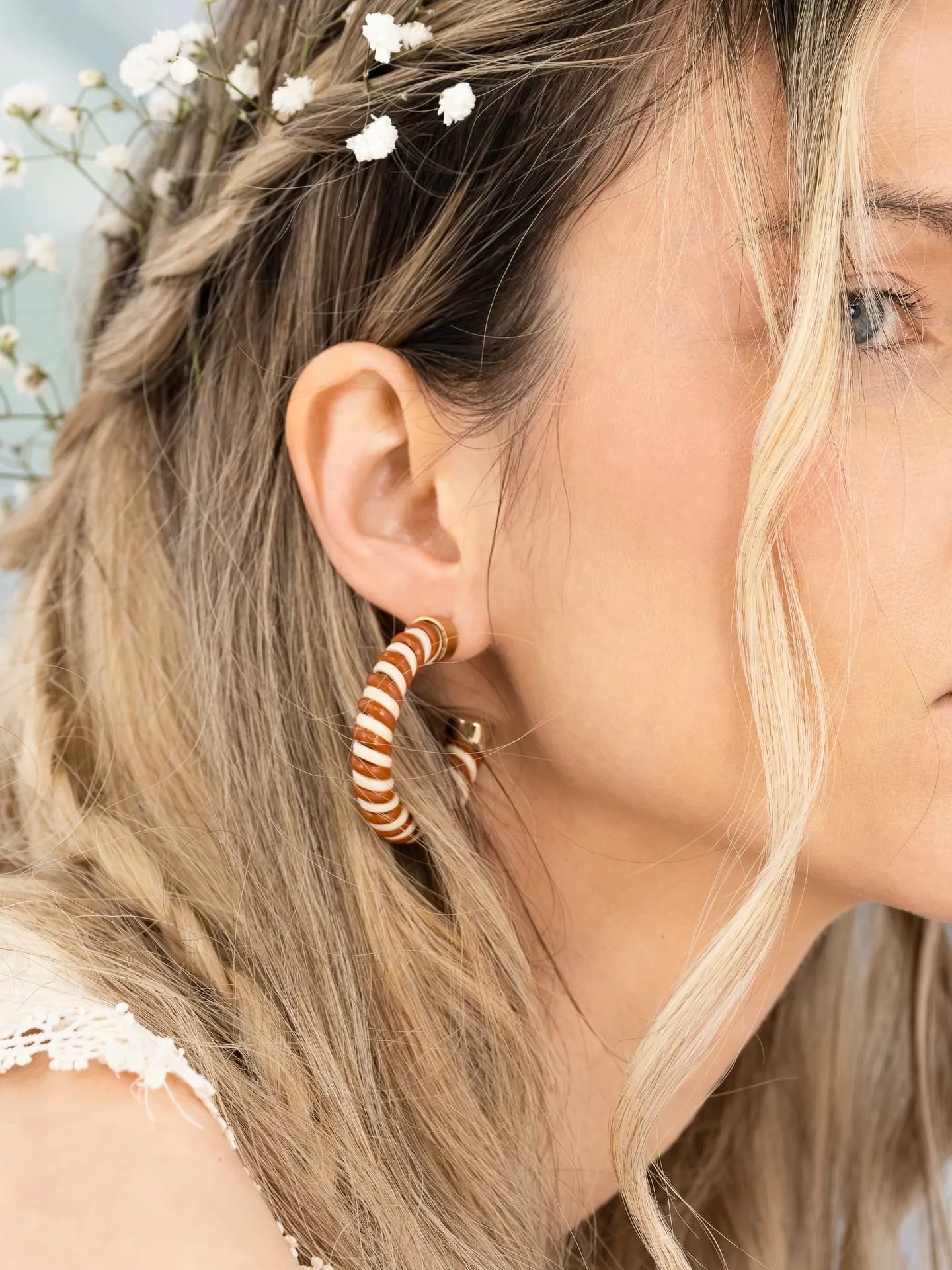 Close portrait with a gold spiral earring and flowers in the hair