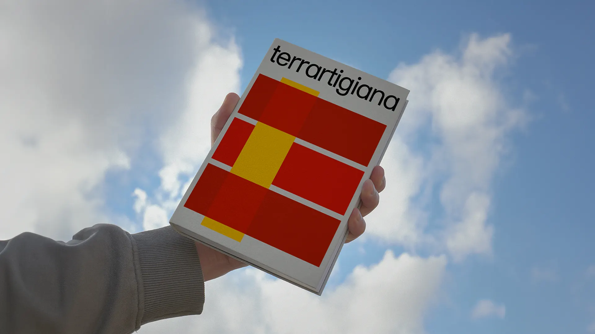 Hand holding the catalogue cover against the sky