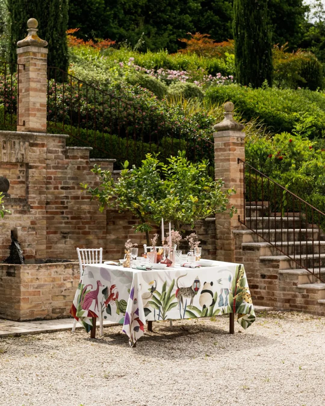 Table on a brick terrace among cypresses, plant-print tablecloth
