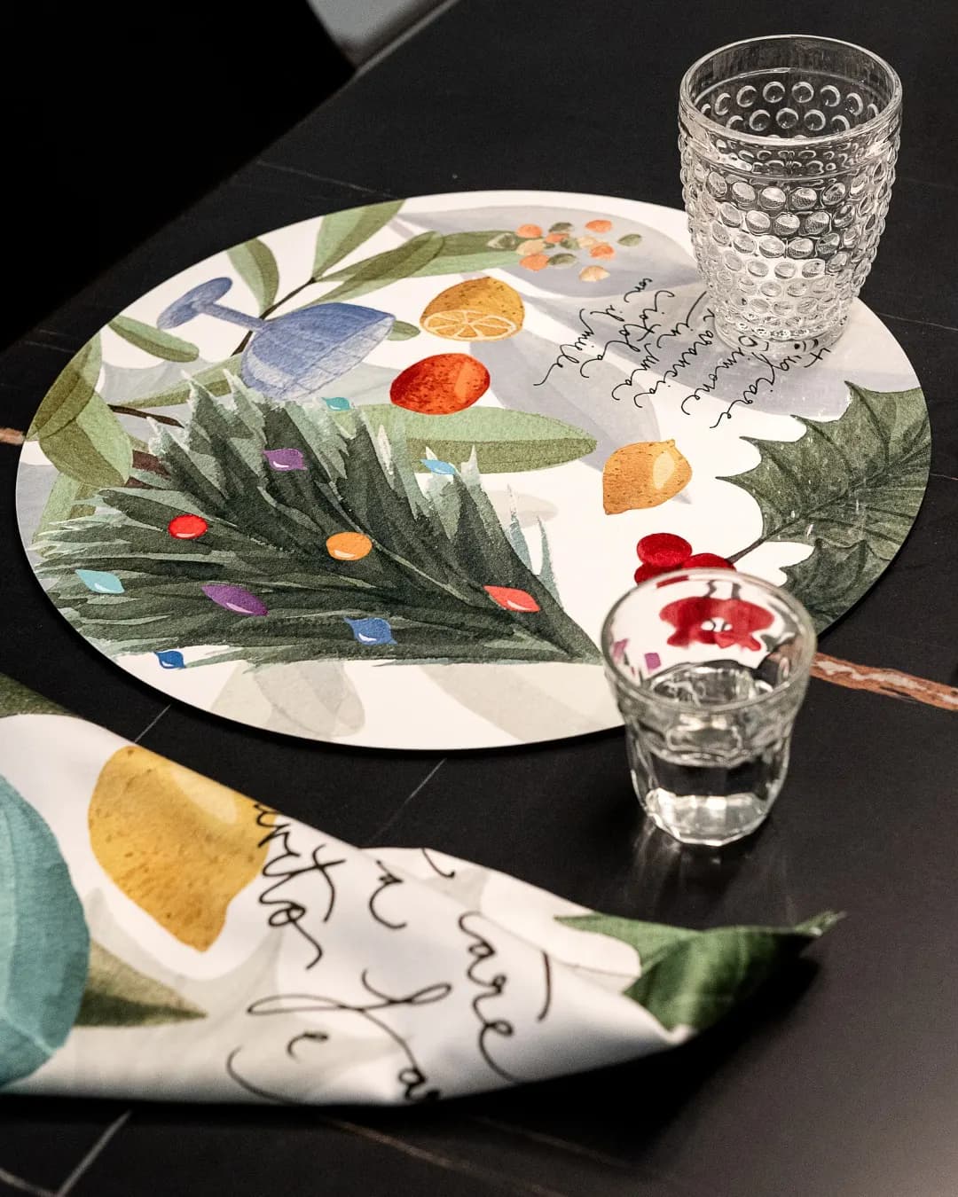 Plate decorated with pine sprigs and a napkin, on a black surface