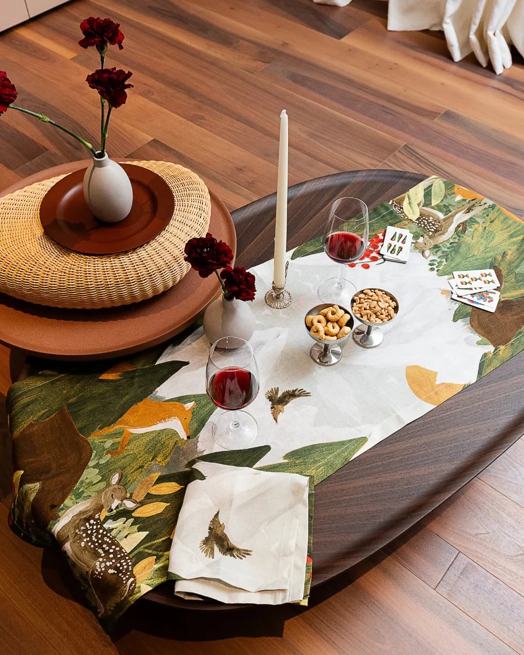 Botanical runner on an oval wooden table, with a basket and candles