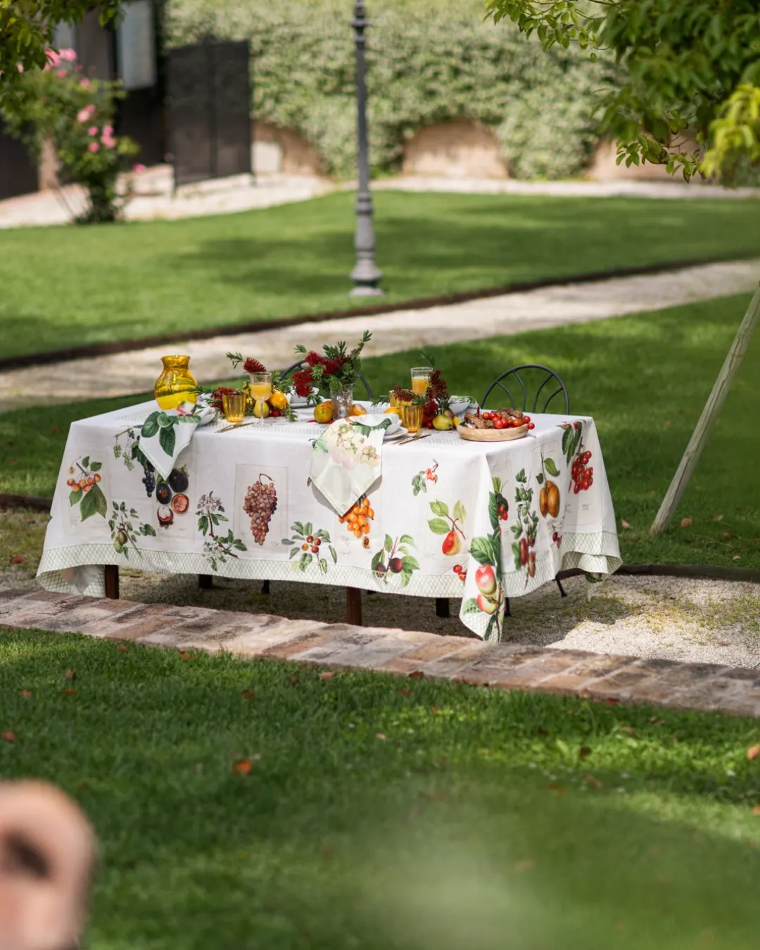 Table laid in the garden under the foliage, botanical print linen tablecloth