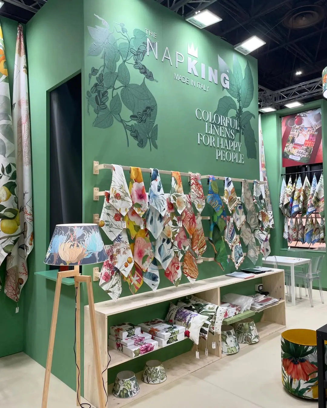 Trade show stand with green walls, hanging fabrics and the Napking sign